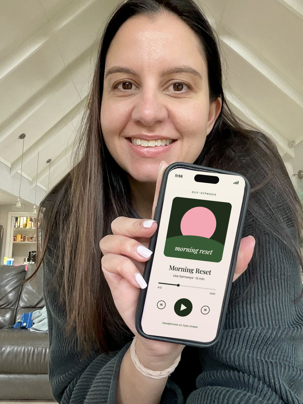 Lisa Samways smiling, holding up her phone playing a hypnosis audio